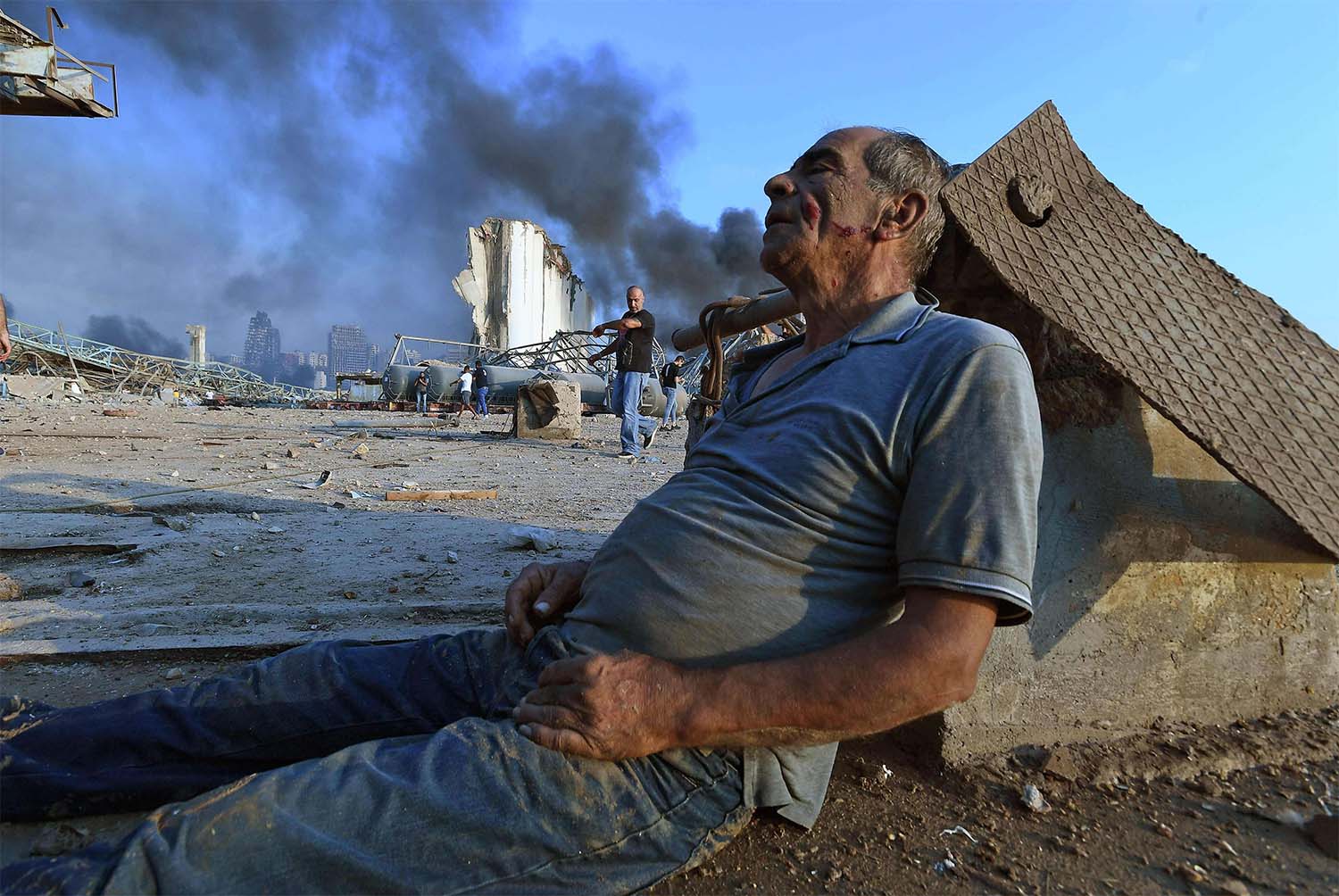 A wounded man sits on the ground waiting for aid at Beirut's port 