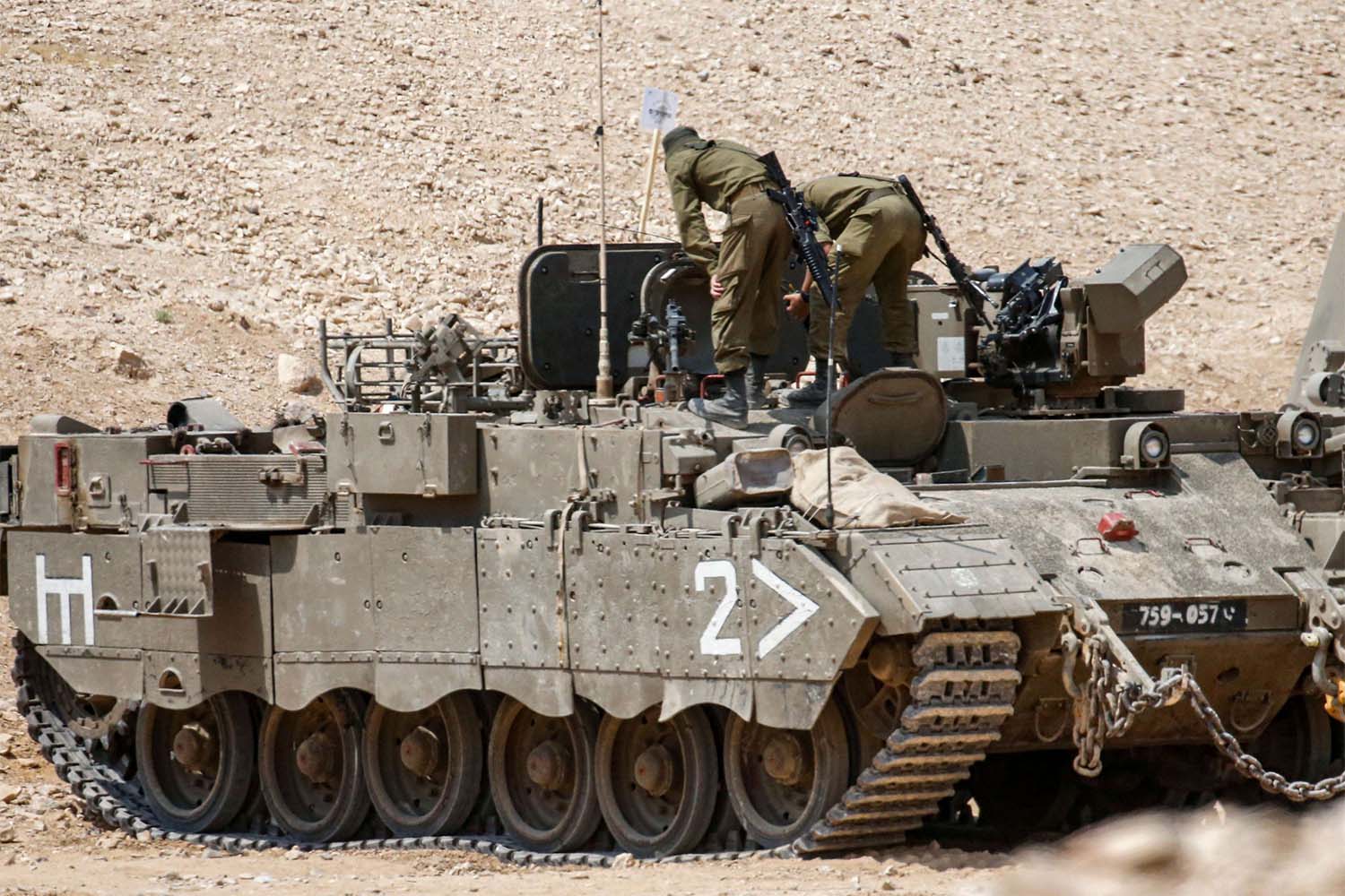 Israeli soldiers standing atop an infantry fighting vehicle (IFV) check their equipment at a military training camp near the village of Yatta 