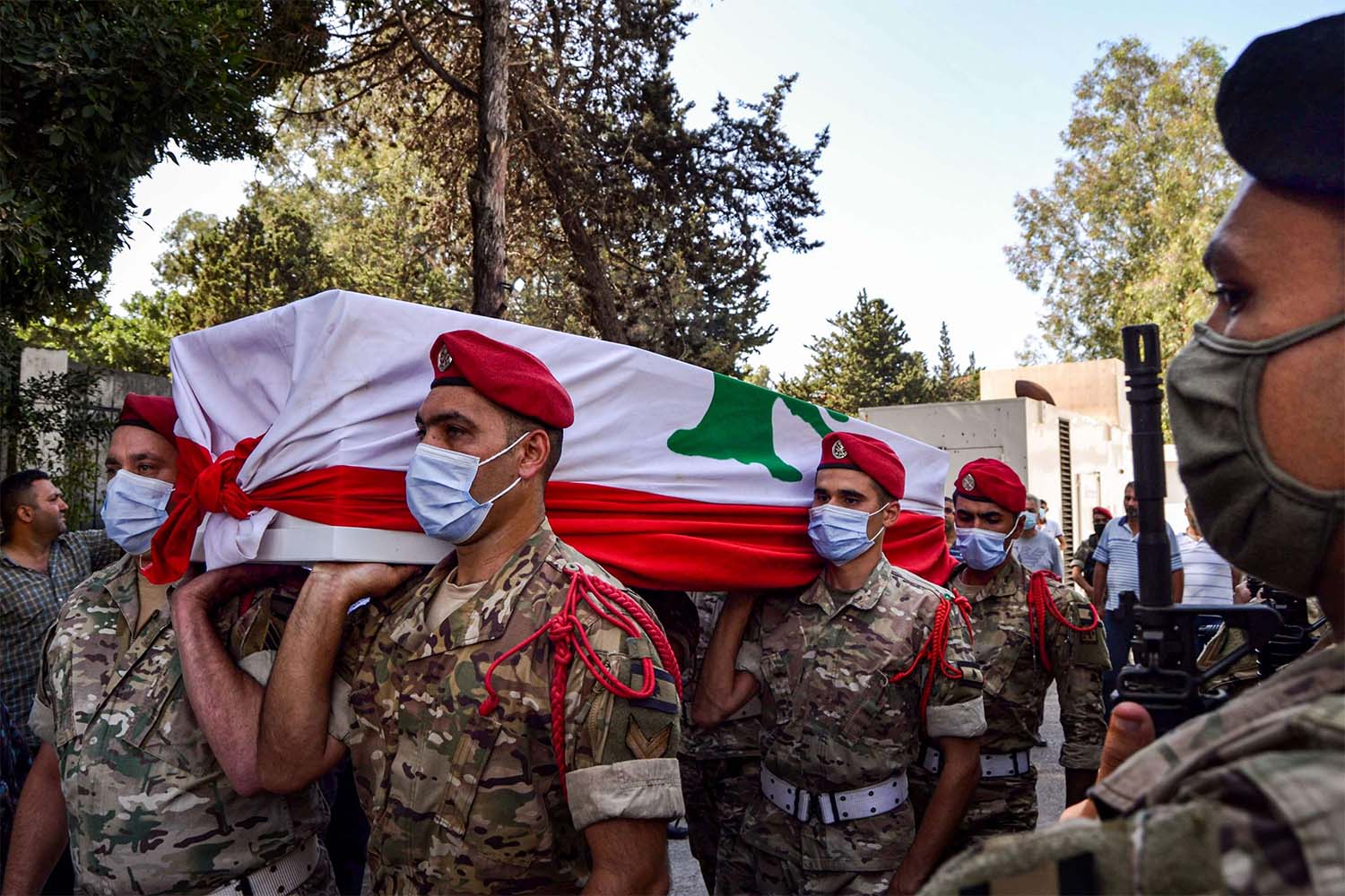 Lebanese army soldiers, clad in masks due to the COVID-19 coronavirus pandemic, carry the flag-draped coffin of their fallen comrade