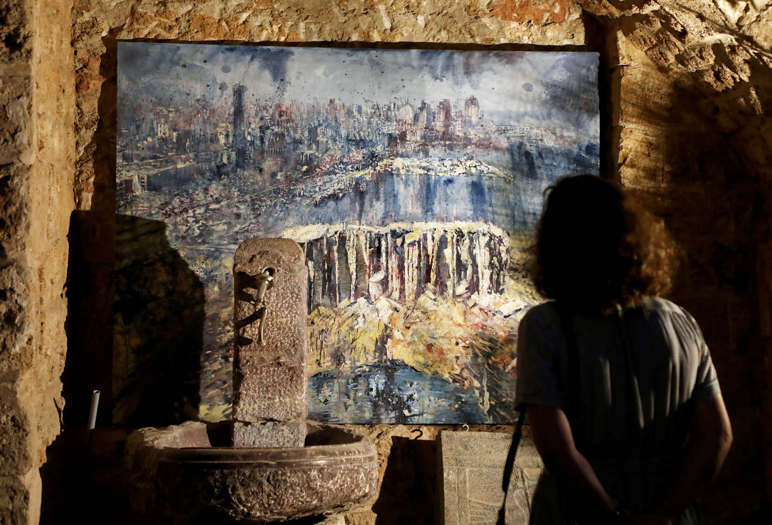 لبنانية تنظر إلى لوحة تصور مشهد الدمار في بيروت