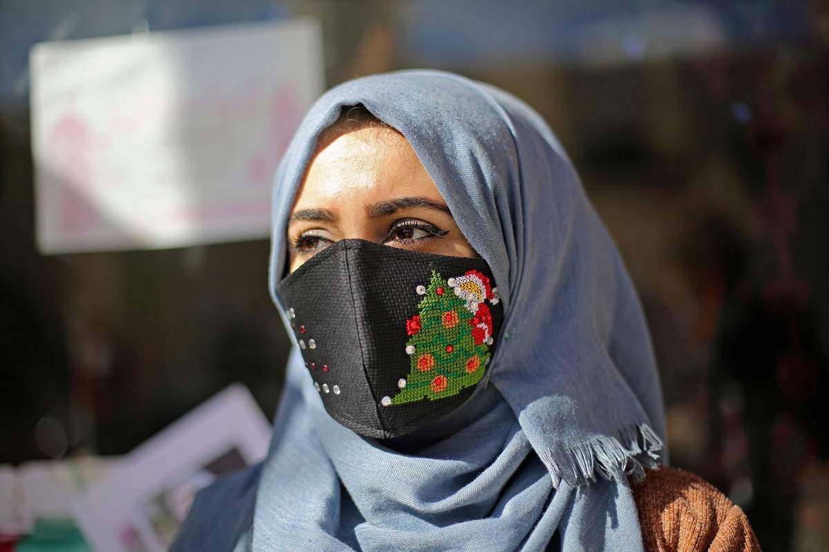 امرأة فلسطينية ترتدي كمامة برسم لرمز لعيد الميلاد في مدينة غزة 