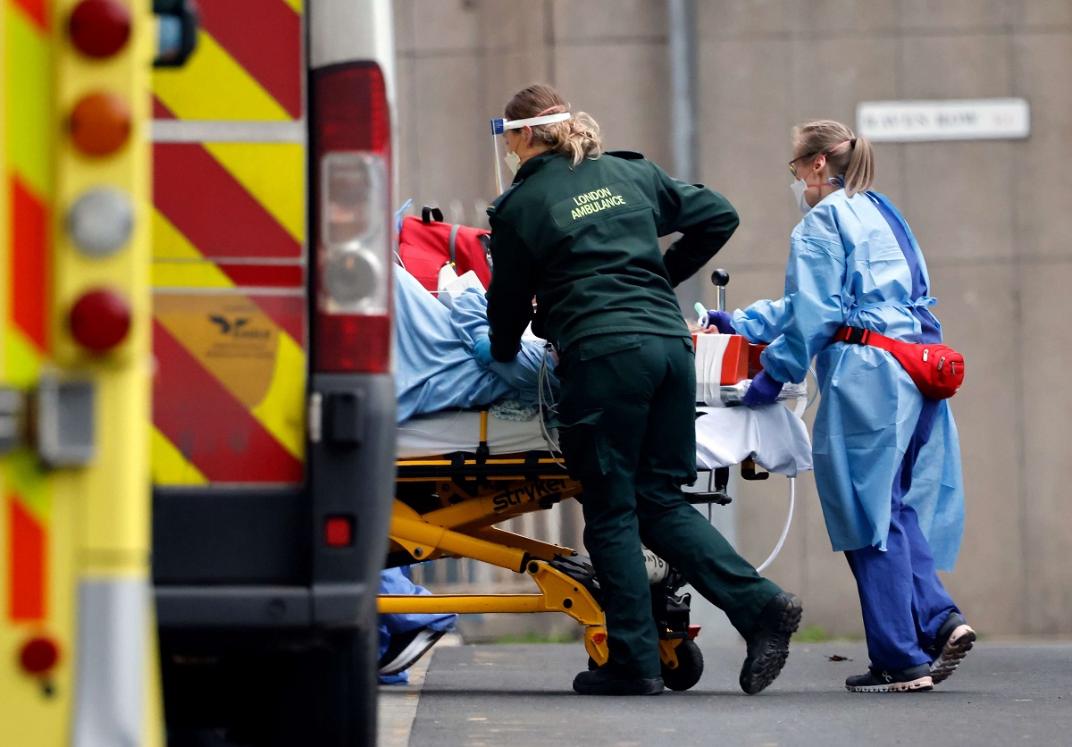 مسعفون ينقلون مريضًا من سيارة إسعاف إلى مستشفى في لندن