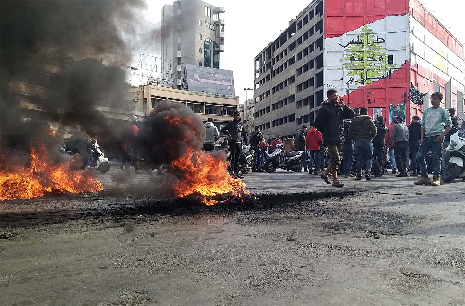 Demonstrators gather near burning tires during a protest against the lockdown and worsening economic conditions