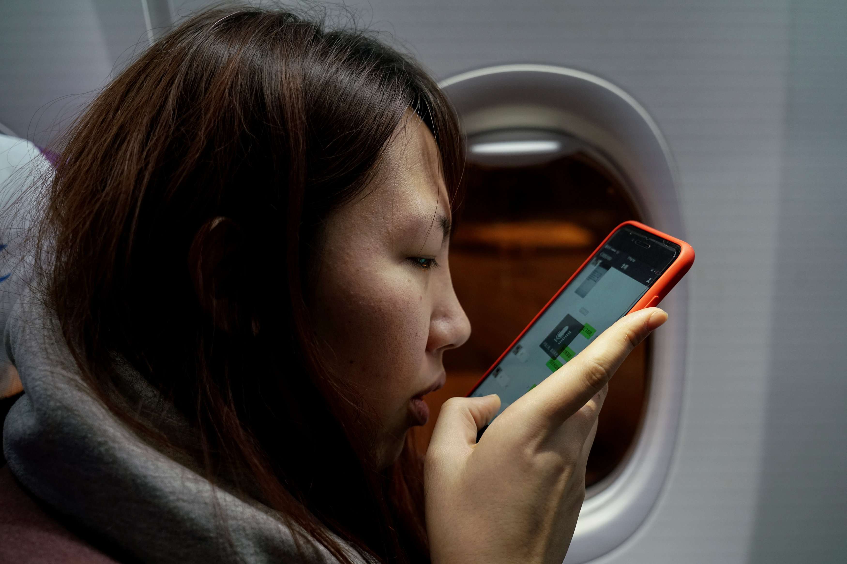 مسافرة صينية تستخدم هاتفها في الطائرة