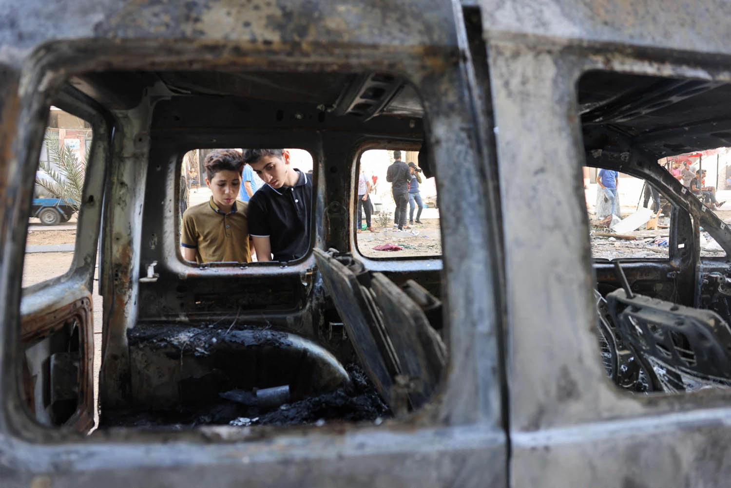 اطفال فلسطينيون ينظرون إلى سيارة محترقة بعد جولة قصف إسرائيلي على غزة