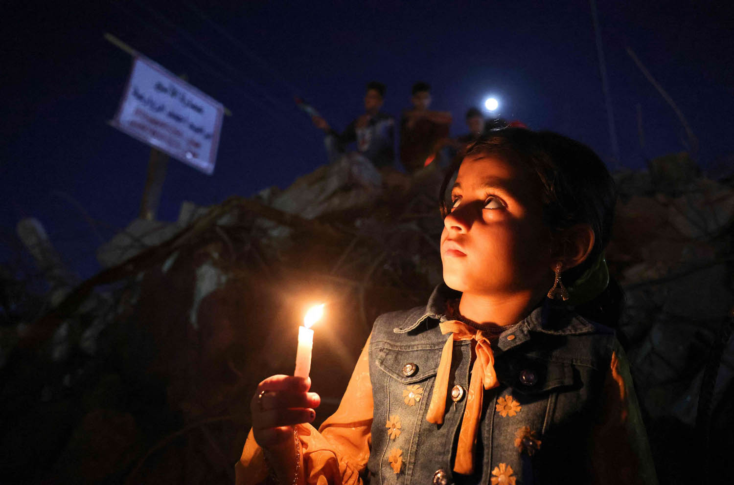طفل فلسطيني يوقد شمعة على اطلال القصف في غزة