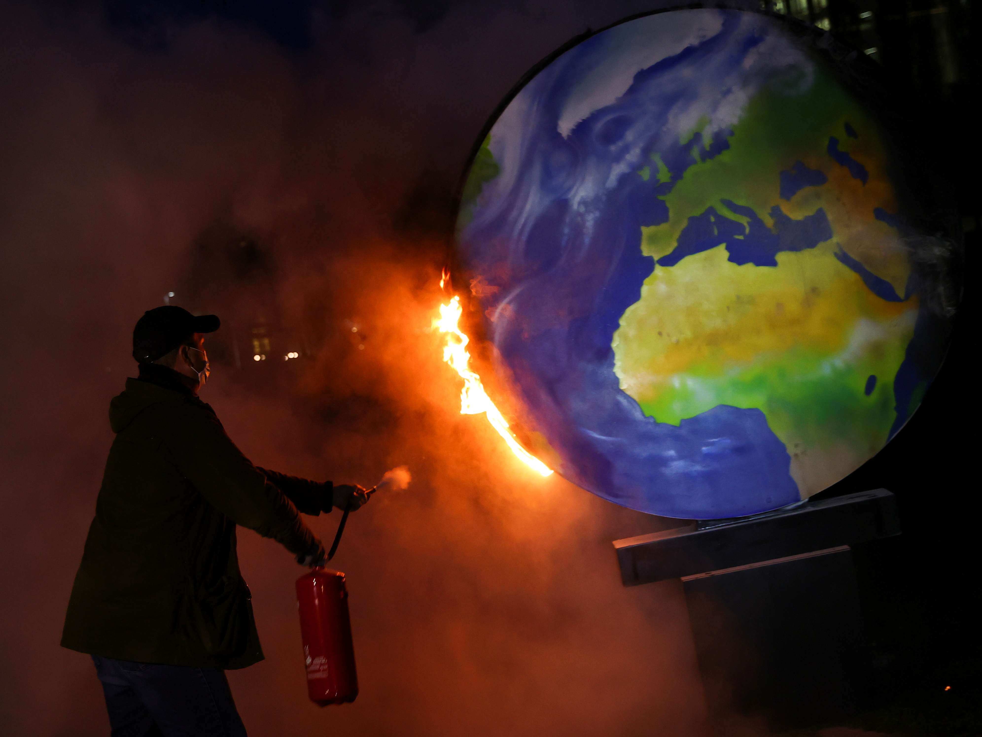 ناشط يطفئ كرة أرضية محترقة من الورق خلال مظاهرة ضد صناعة الوقود الأحفوري في ألمانيا