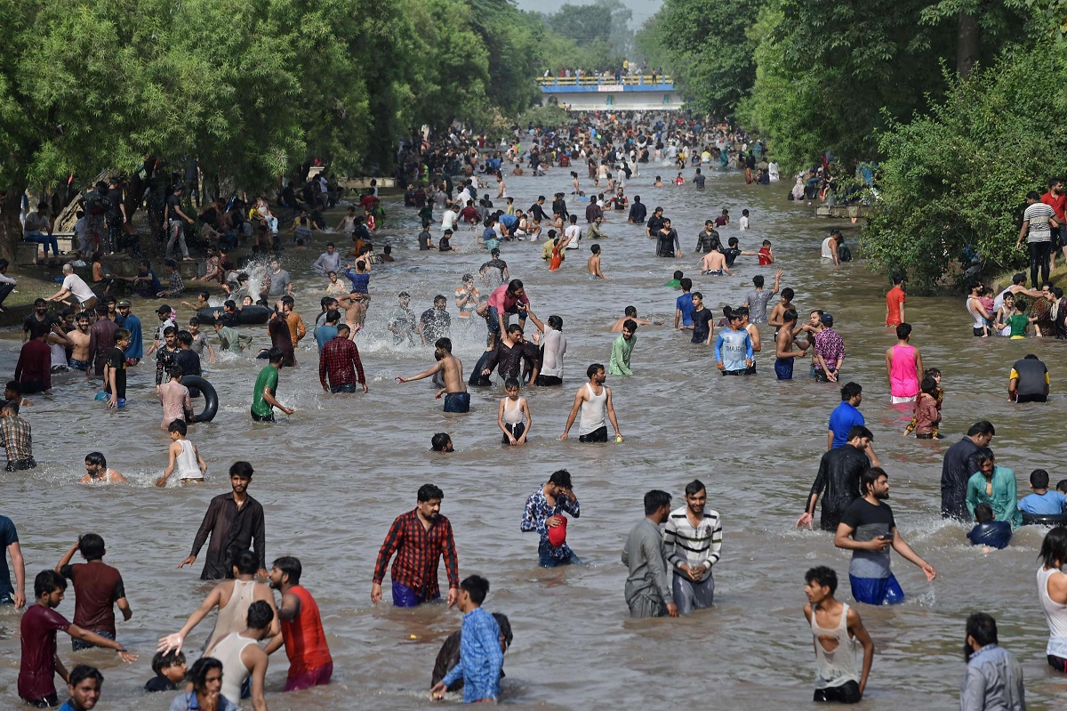 باكستانيون يبردون أنفسهم في قناة في يوم صيفي حار في لاهور في مايو 2021
