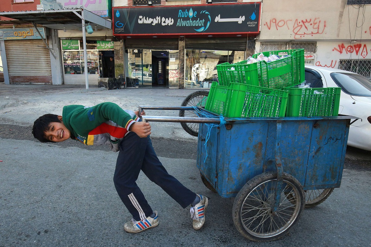 طفل اردني يجر عربة يدوية للعمل في عمان 