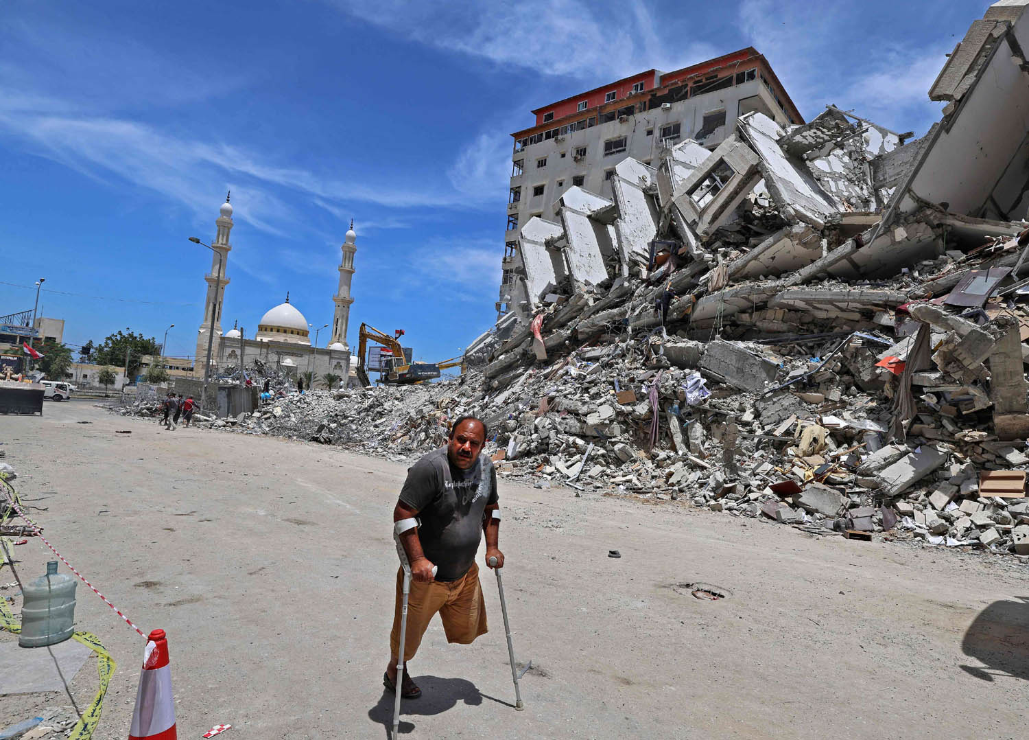 فلسطيني معوق يمر بجانب بناية دمرها القصف الإسرائيلي في غزة