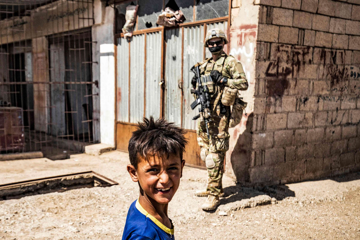طفل كردي سوري مع جندي أميركي في قرية شمال سوريا