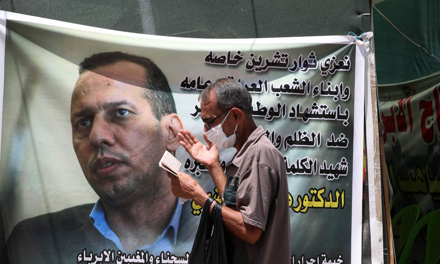 عراقي يمر بجانب ملصق للشهيد هشام الهاشمي في بغداد