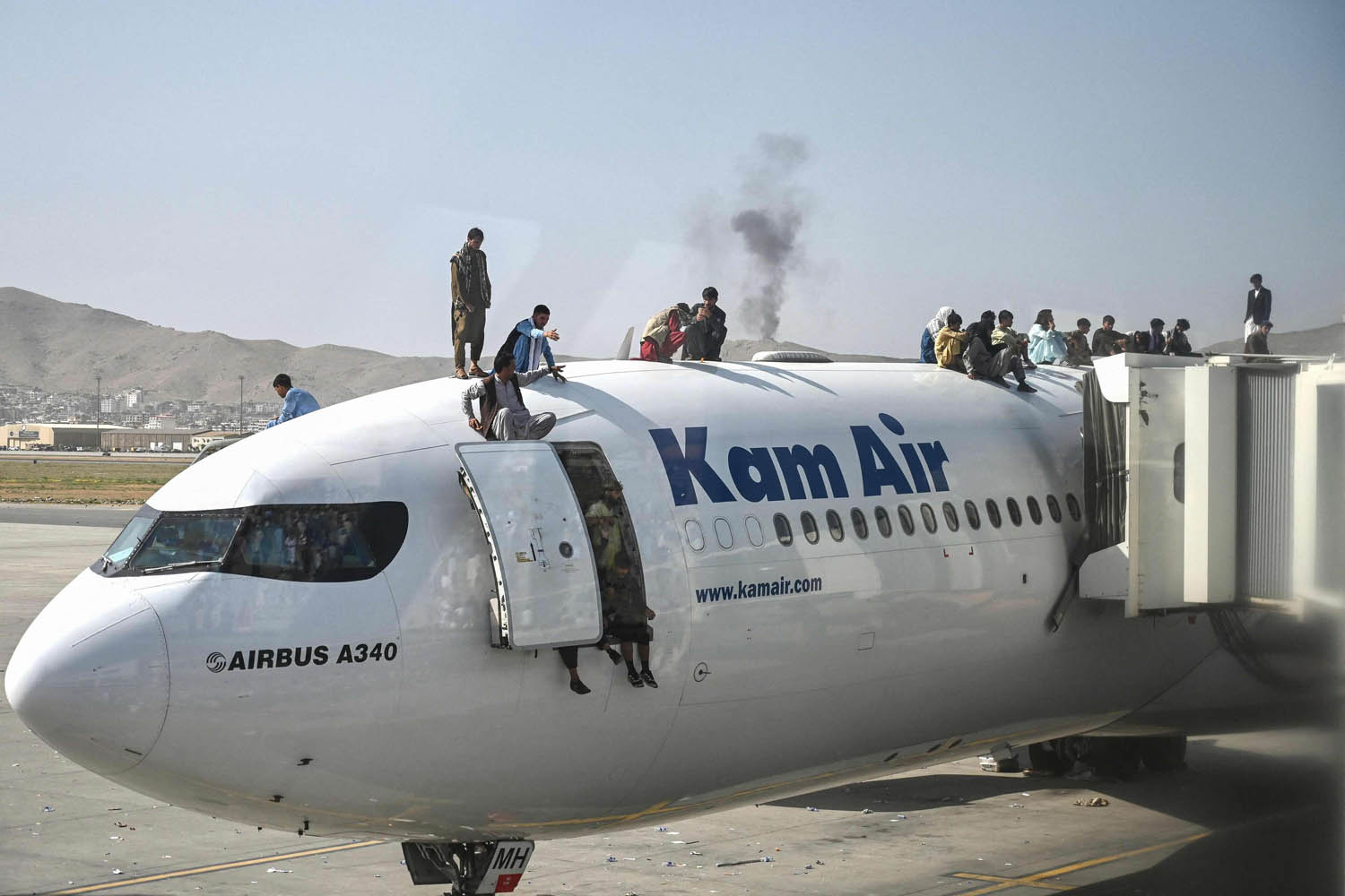 افغان يعتلون ظهر طائرة في مطار كابول