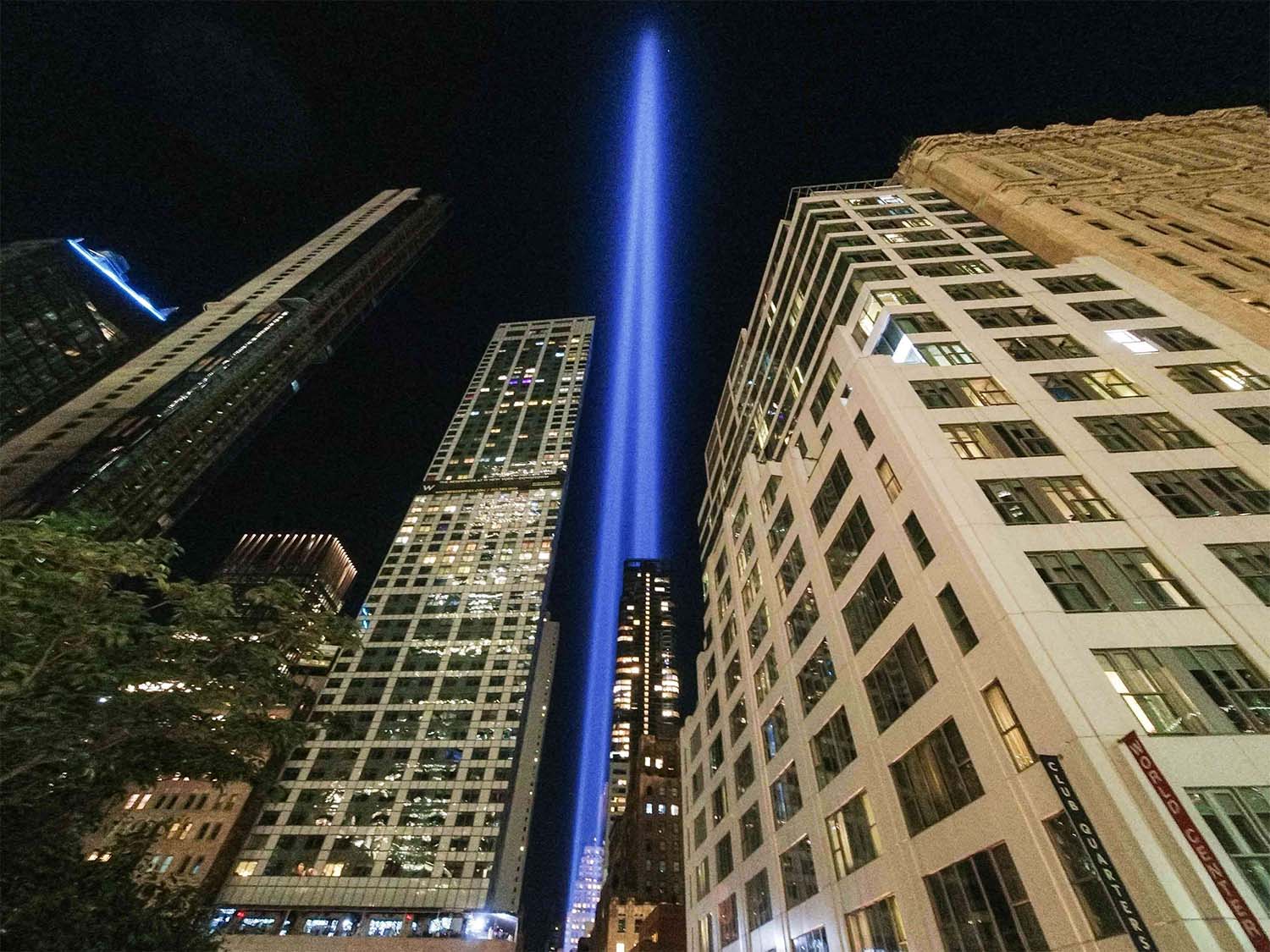 The annual Tribute in Light projects two pillars of light into the night sky next to the buildings overlooking the 9/11 Memorial & Museum in New York City
