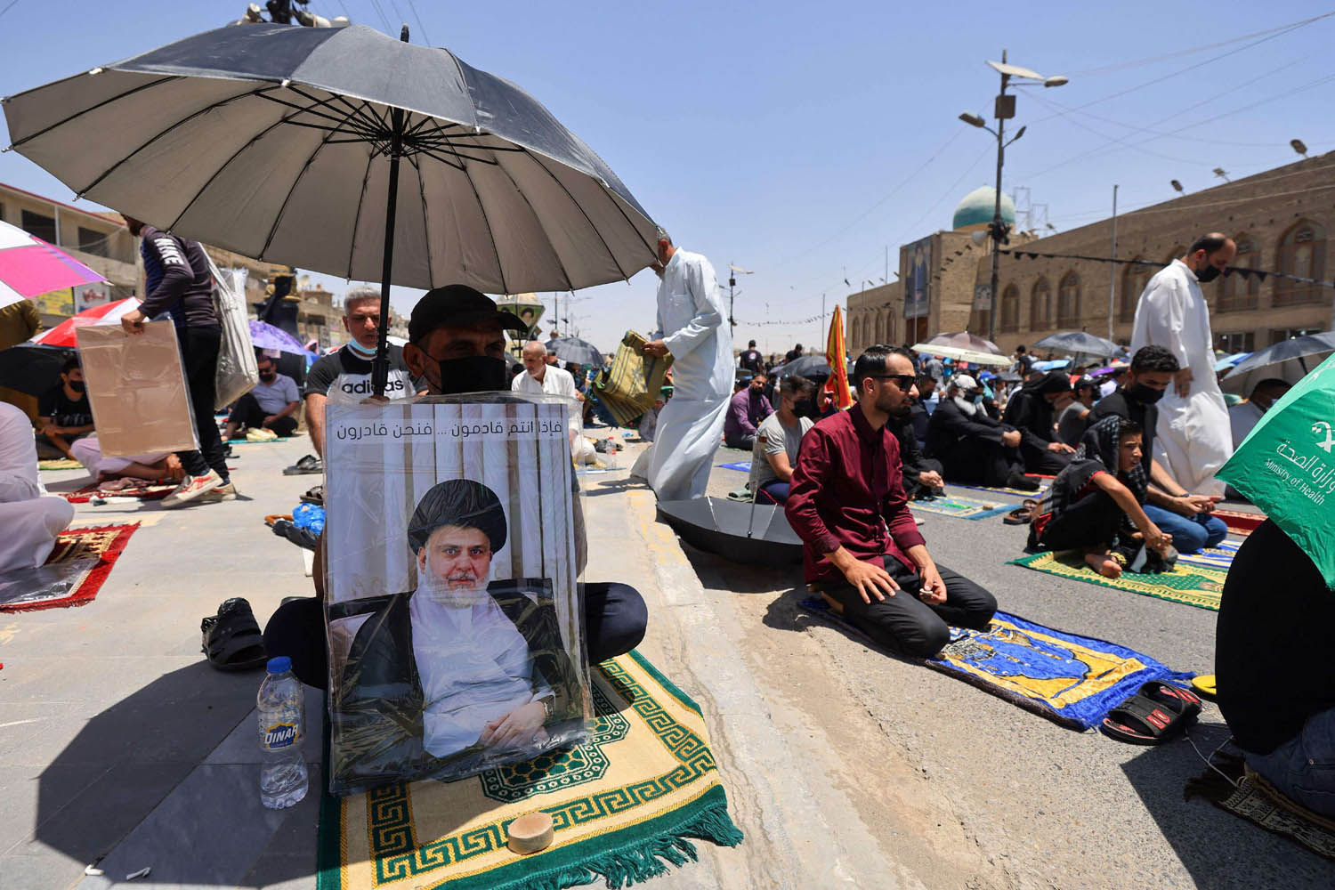 عراقيون يرفعون صورا للصدر أثناء صلاة الجمعة في مدينة الصدر في بغداد