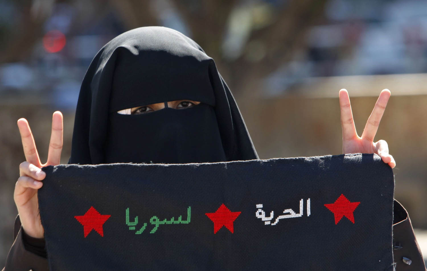 فلسطينية من حركة حماس في غزة ترفع شعارا مؤيدا للثورة على نظام الأسد