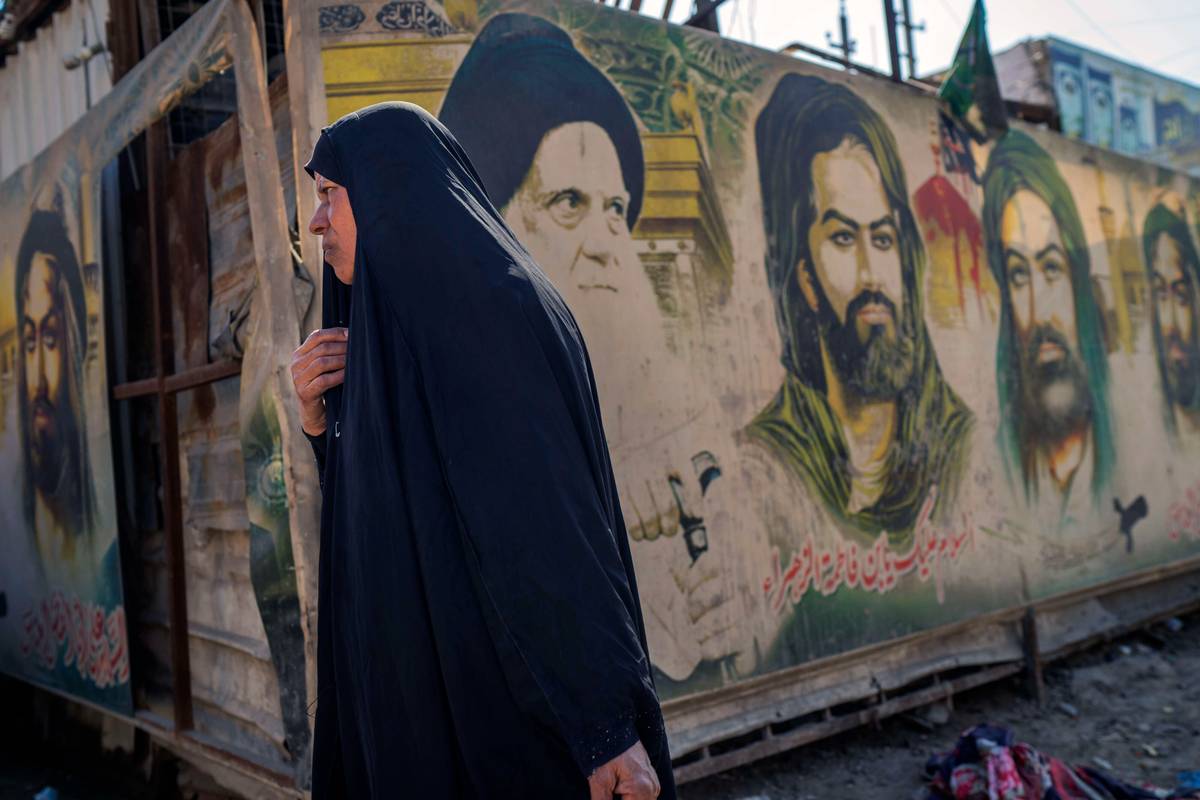 عراقية تمر بجانب جداريات لصور أئمة شيعة في مدينة الصدر ببغداد