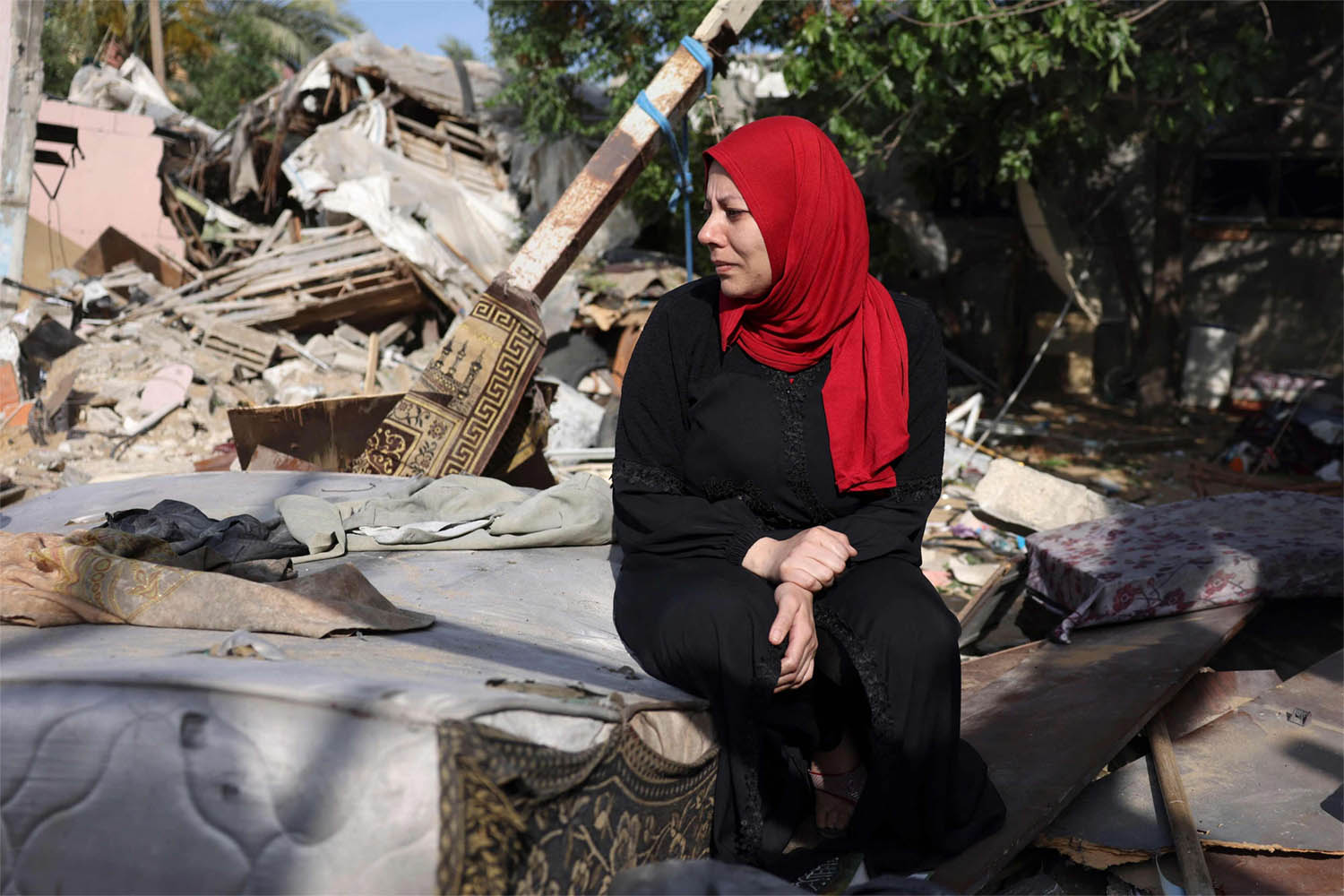A woman sits amidst the rubble of her house at Nusseirat refugee camp in Gaza