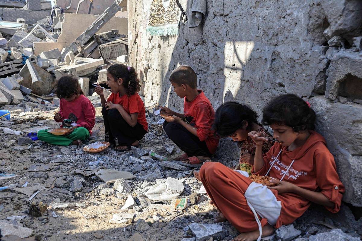أطفال فلسطينيون يأكلون بين انقاض منازل مدمرة بالقصف الإسرائيلي