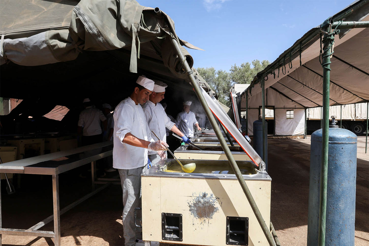 en prepare meals for displaced people residing in a military aid camp following the deadly earthquake in Amizmiz in September 2023