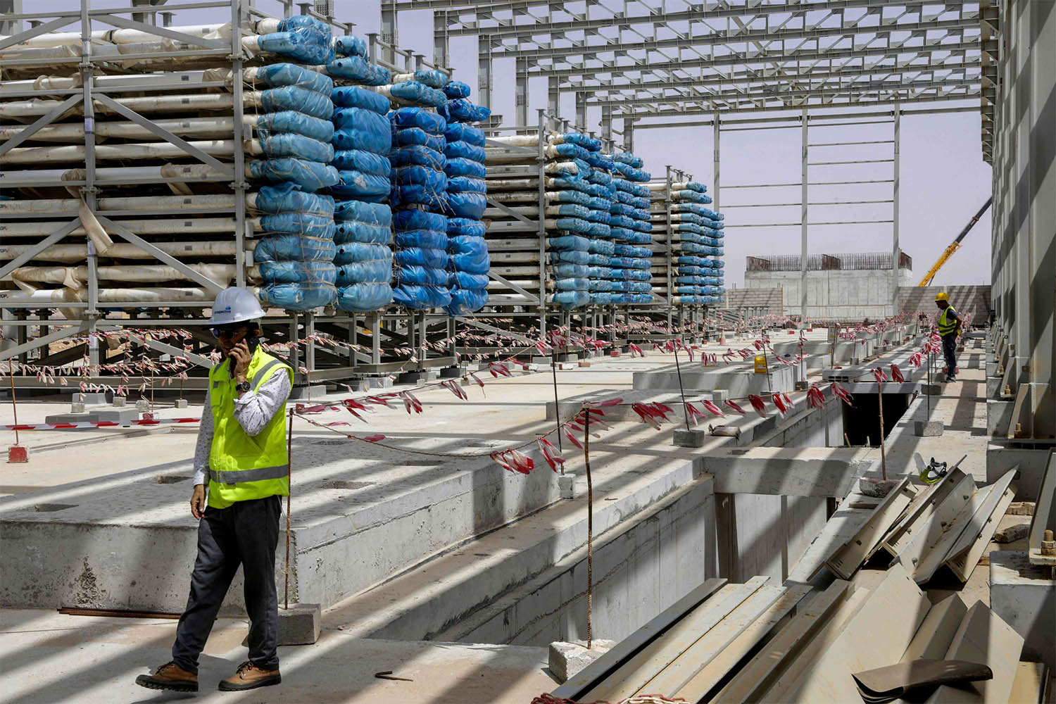 Workers stand near next to heavy equipment during the construction of a desalination plant in Dakhla