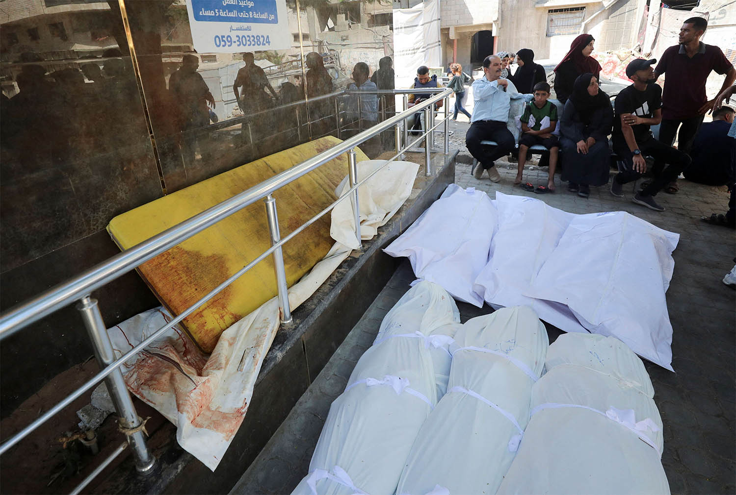 Mourners sit next to dead bodies during the funeral of Palestinians killed in an Israeli strike 