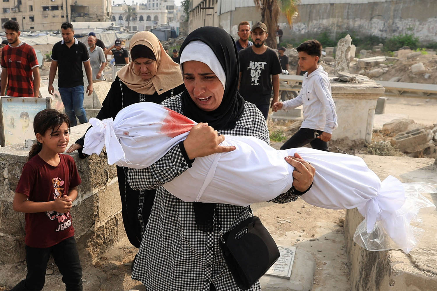 Palestinian woman Soha Tafesh carries the body of her granddaughter Sarah Abu Daf, who was killed in an early morning Israeli strike on a house