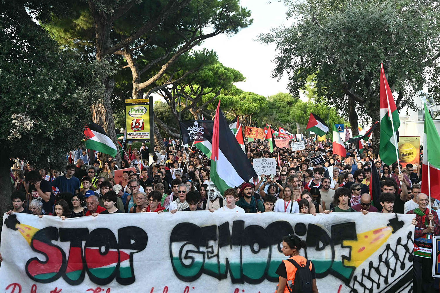 People march behind a banner reading Stop Genocide as part of a demonstration in support of Gaza and Palestinian people at Venice Lido