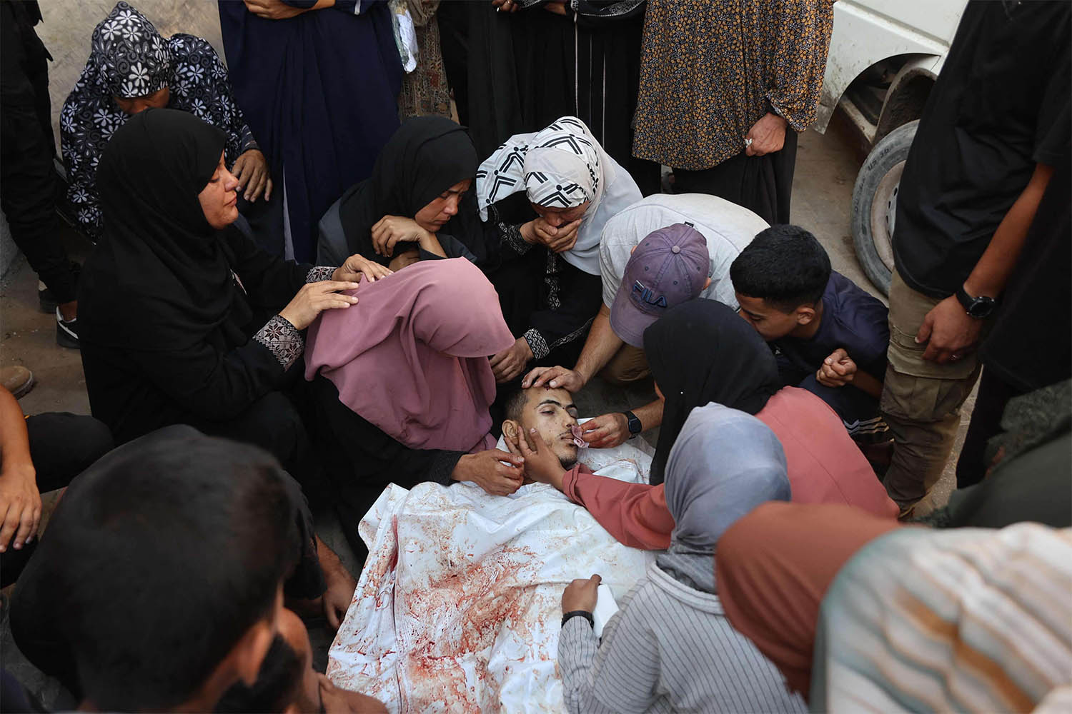 Palestinians mourn by the body of a relative killed in Israeli strikes on Gaza City at dawn