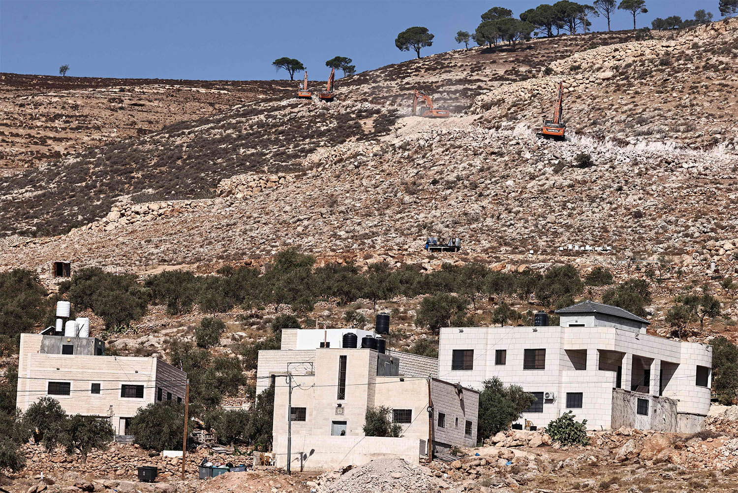 Israeli settlers use bulldozers to pave a road for a new settlement on the outskirts of the occupied West Bank village of Al-Mughayyir, north of Ramallah
