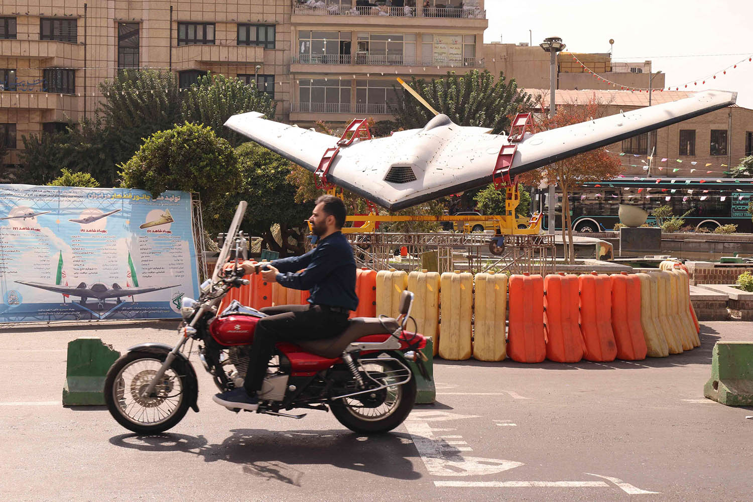 An Iranian man rides his motorcycle past a Shahed drone in Tehrans Bahrestan Square on September 27, 2025, as part of an exhibit to mark the Sacred Defense Week commemorating the 1980-88 Iran-Iraq war