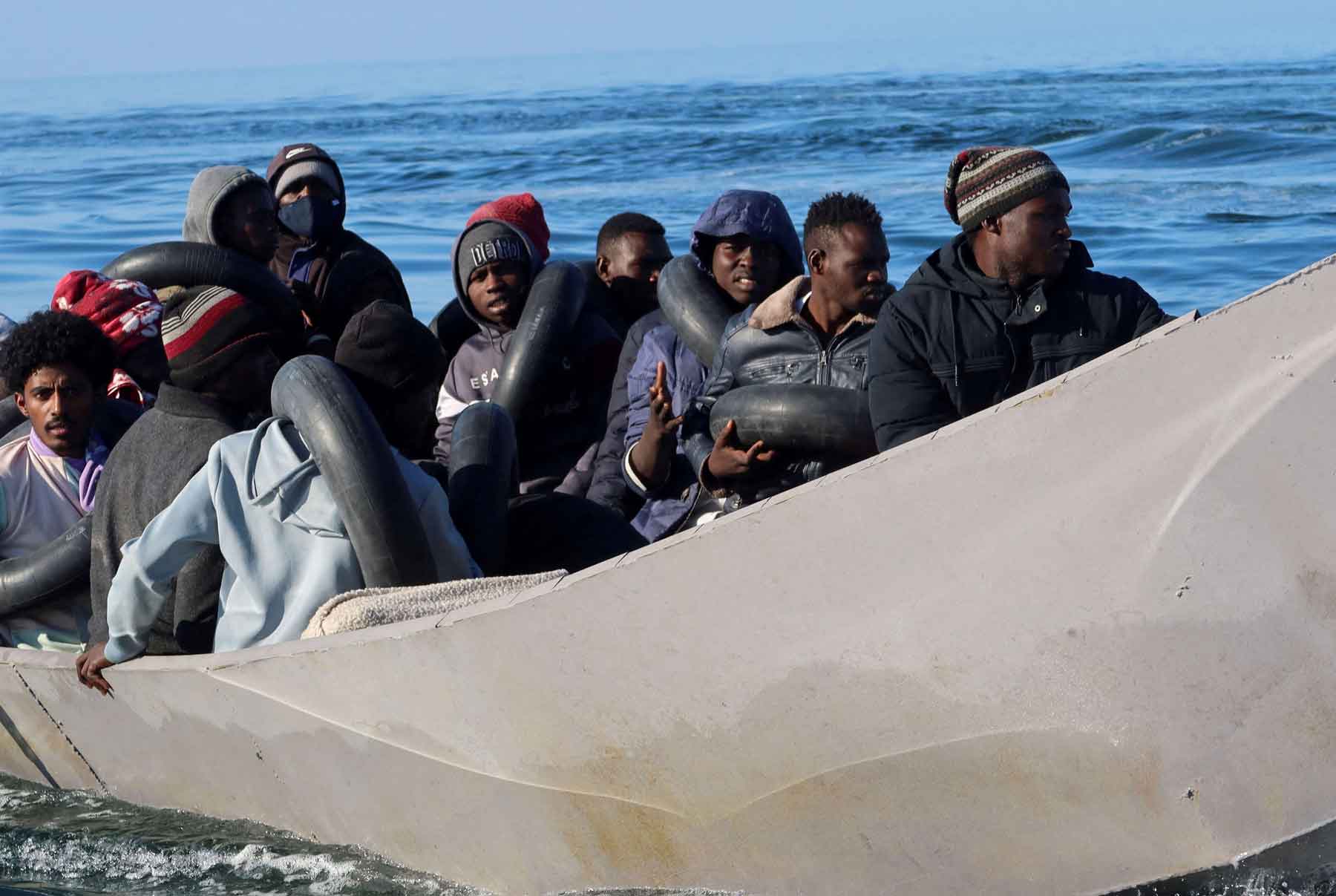 Migrants are pictured on a metal boat as Tunisian coast guards try to stop them at sea during their attempt to cross to Italy, off Sfax, Tunisia. 