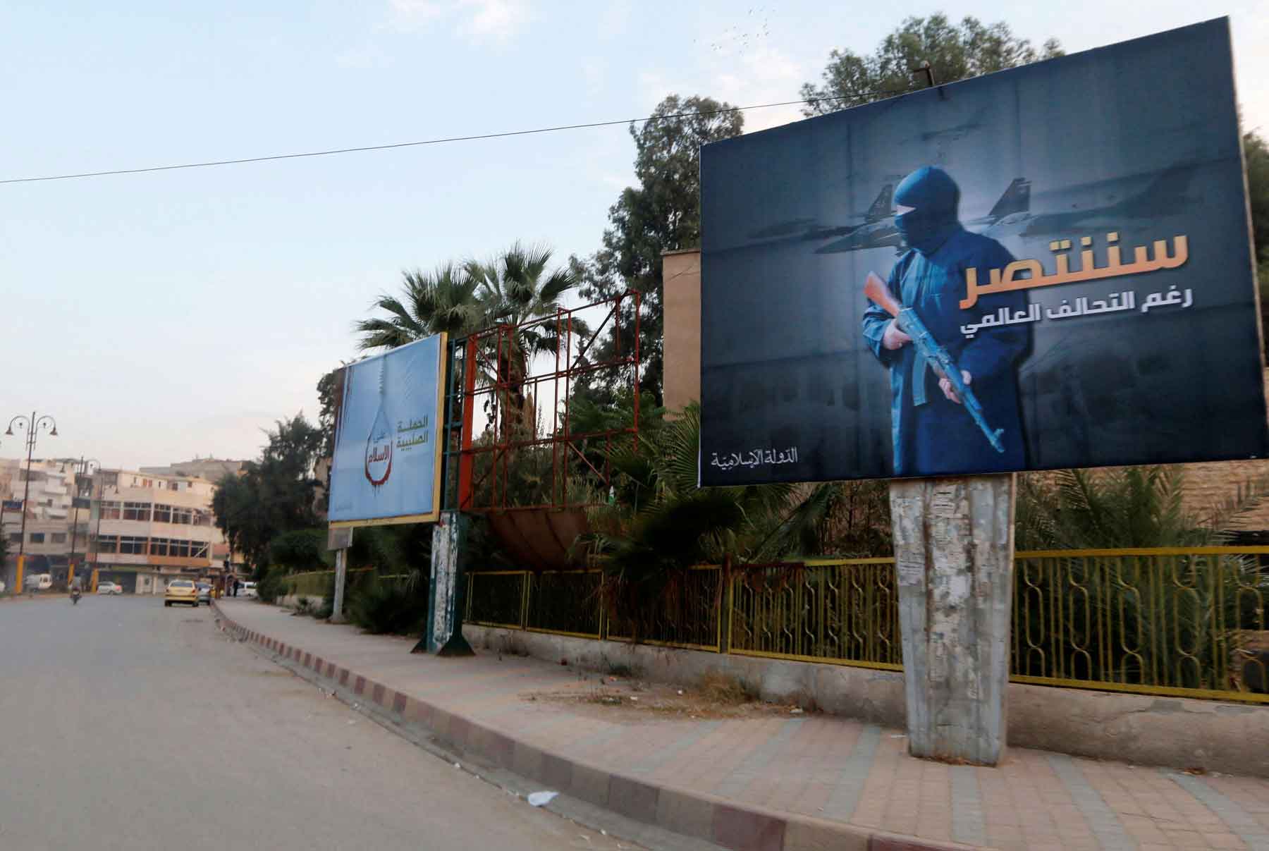A 2014 file picture shows Islamic State billboards are seen along a street in Raqqa, eastern Syria. The billboard (R) reads: “We will win despite the global coalition.” 