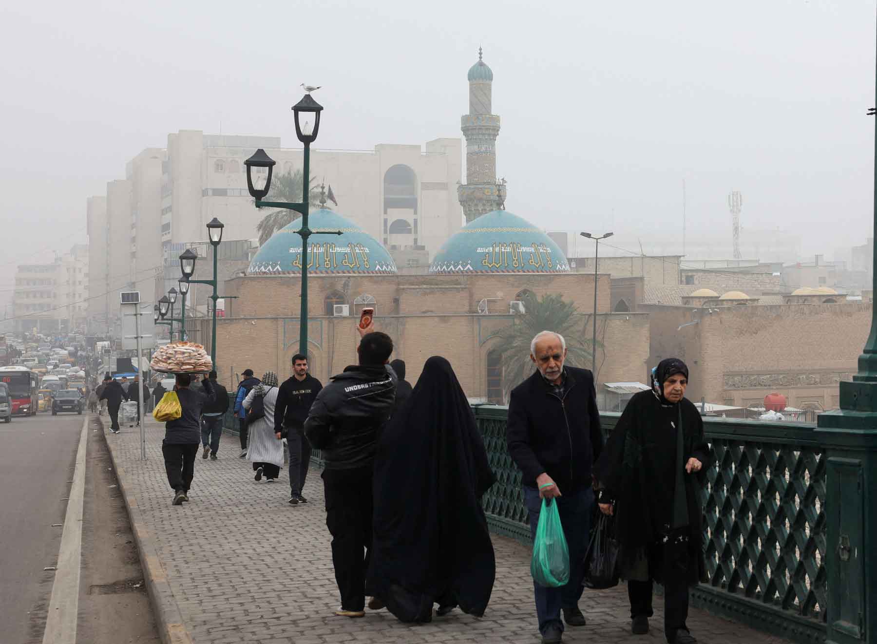 People walk across a bridge during a foggy day in Baghdad, December 11, 2025. 