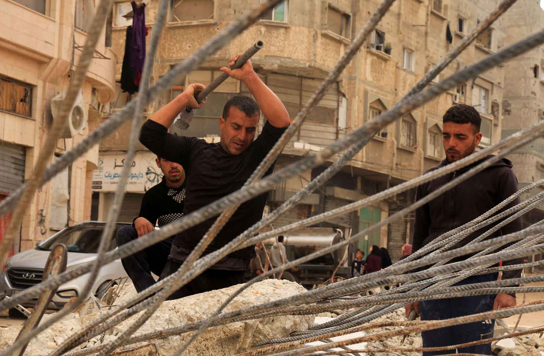 Palestinian workers break concrete to extract steel bars from destroyed homes amid a severe shortage of construction materials, in Khan Younis in the southern Gaza Strip, December 9, 2025. 