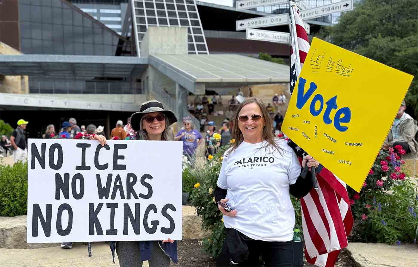 Two protesters hold signs, one reading “No ICE, No Wars, No Kings”, at the No Kings protest against Trump's administration policies in Austin, Texas