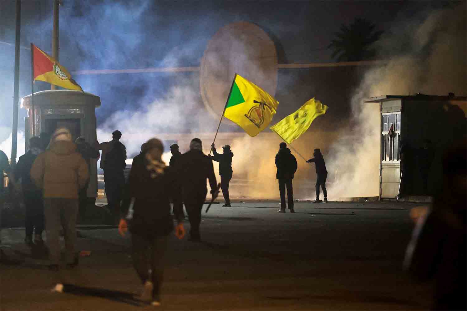 A protester holds a Kataib Hezbollah flag as supporters of Iraqi Shiite armed group's attempt to move toward the US embassy in Baghdad
