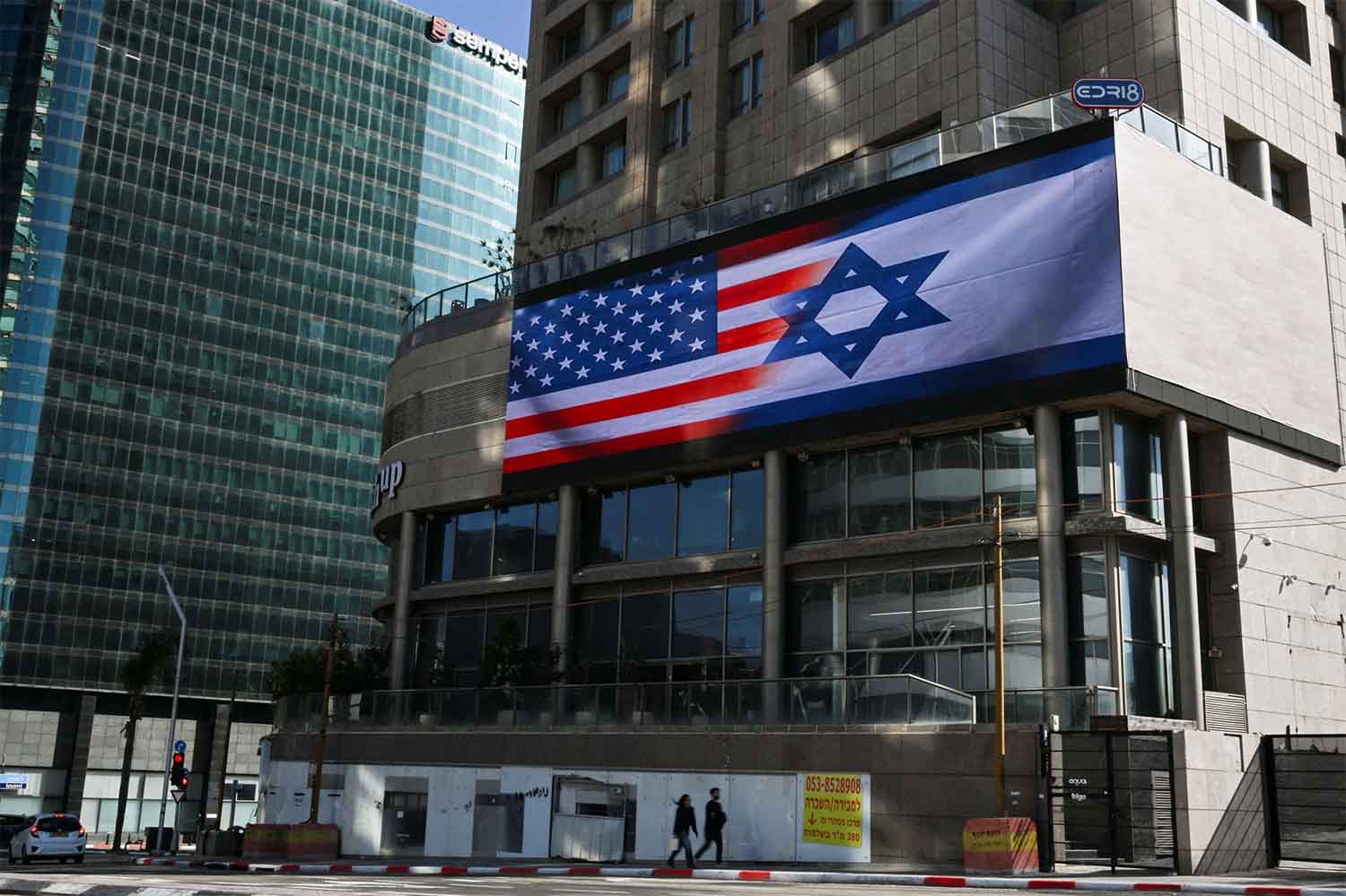A screen displays Israeli and American flags in Tel Aviv