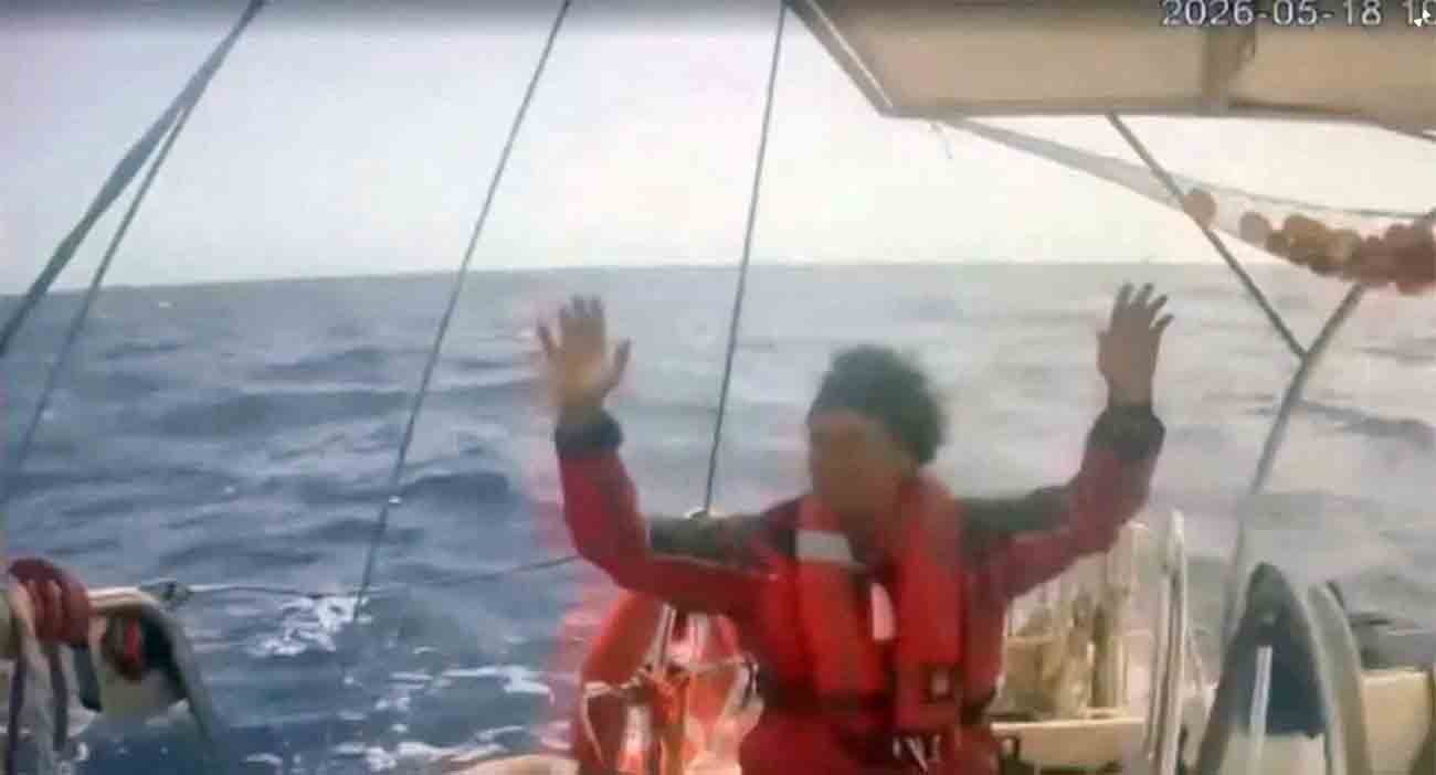 An activist raises his hand as an Israeli naval boat intercepts the Global Sumud Flotilla en route to Gaza, in an attempt to deliver aid, at sea