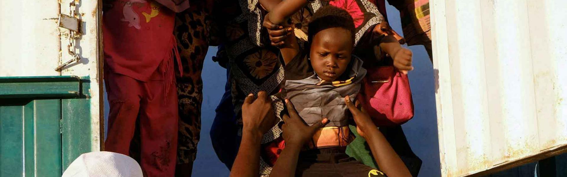 A displaced boy from al-Fashir gets down from a truck, at a displacement camp in Al-Dabba, Sudan, November 19, 2025. 