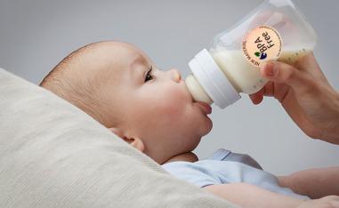 رضيع يشرب الحليب من رضاعة بلاستيكية