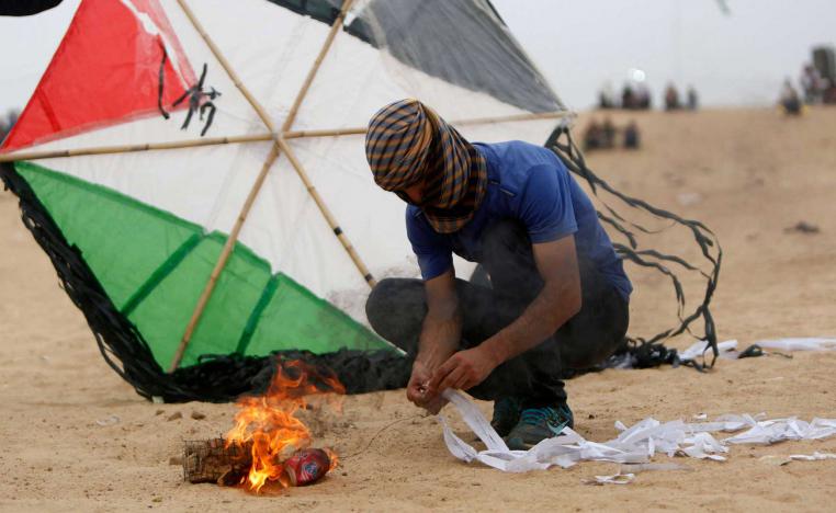 فلسطيني يجهز طائرة مشتعلة قبل قبل محاولة ارسالها الى ما بعد السياج الحدودي مع إسرائيل