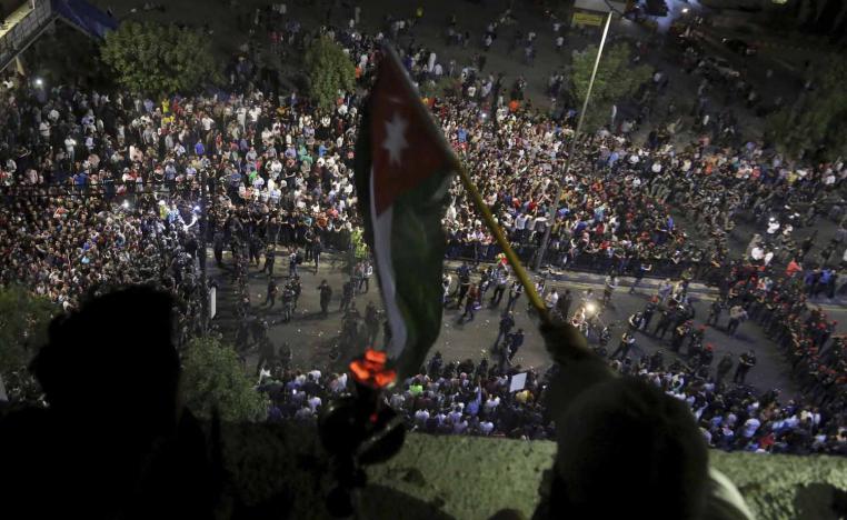 أردنيون يلوحون بعلم بلادهم من فوق بالكونة تطل على جمع متظاهر
