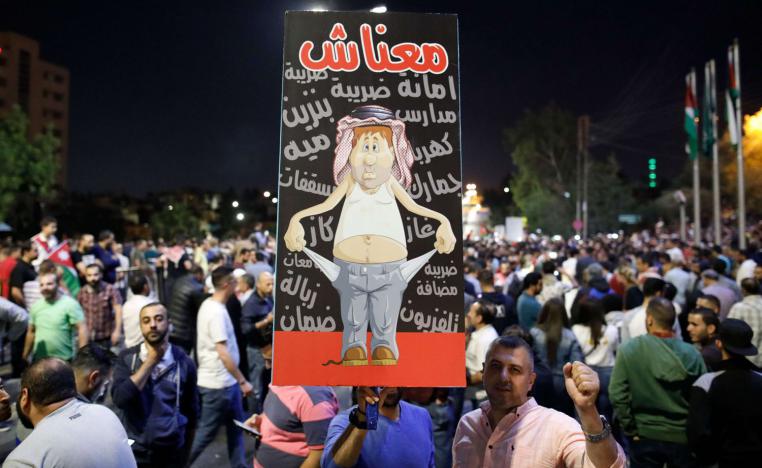 متظاهر أردني يرفع لافتة بالقرب من مقر الحكومة