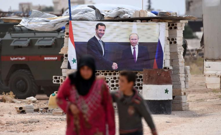 سيدة سورية تمر بجانب ملصق للرئيسين بوتين والأسد