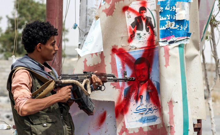 مقاتل يمني من المقاومة الشعبية يوجه بندقيته لصور للحوثي