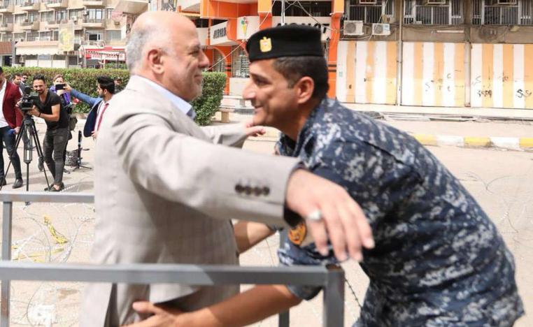 شرطي يفتش رئيس الوزراء العراقي أمام مركز انتخابي