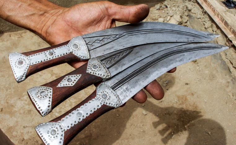A Yemeni man holds newly-formed daggers, created by recycling scrap metal of fallen rockets from air strikes, in the northern district of Yemen's Hajjah province on July 28, 2018.