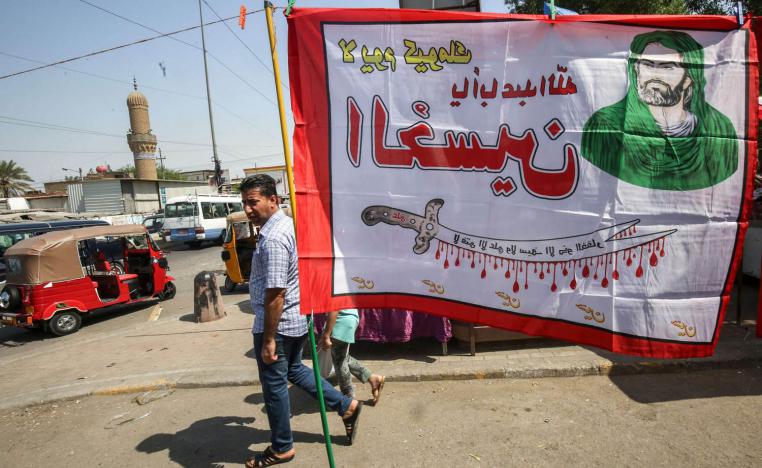 عراقي يمر بالقرب من لافتة طائفية في مدينة الصدر ببغداد