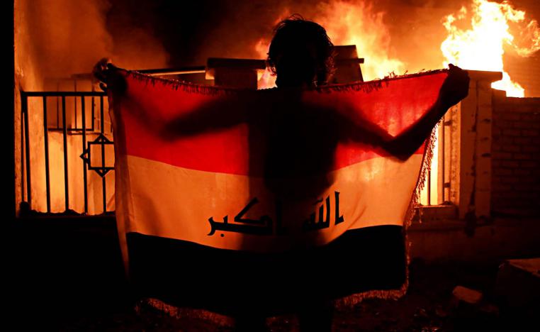عراقي يرفع علما أمام مبنى البلدية المحترق في البصرة